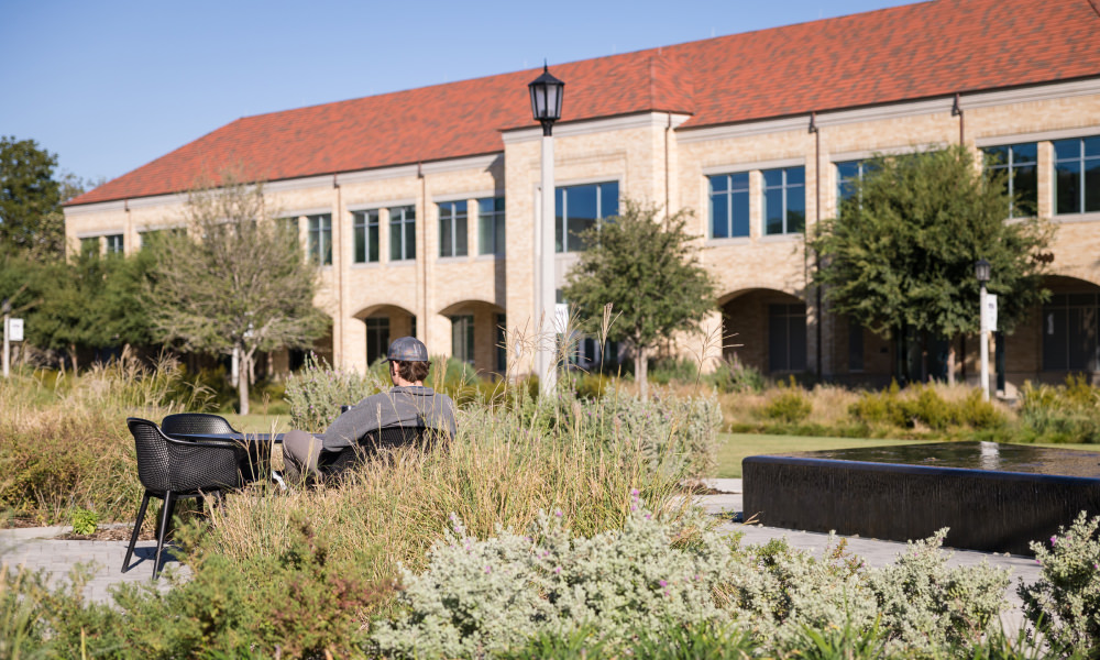 student sitting on campus enjoying the nice weather.